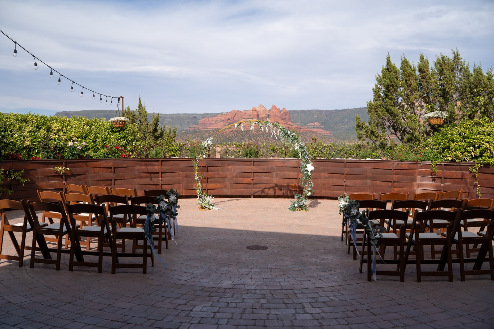 Outdoor Sedona wedding ceremony with wooden chairs, a floral arch, and red-rock views